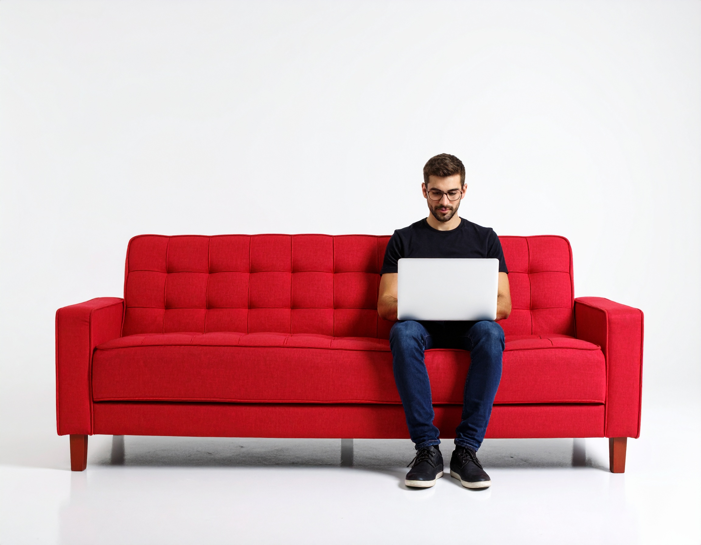 man sitting on a couch working on a laptop