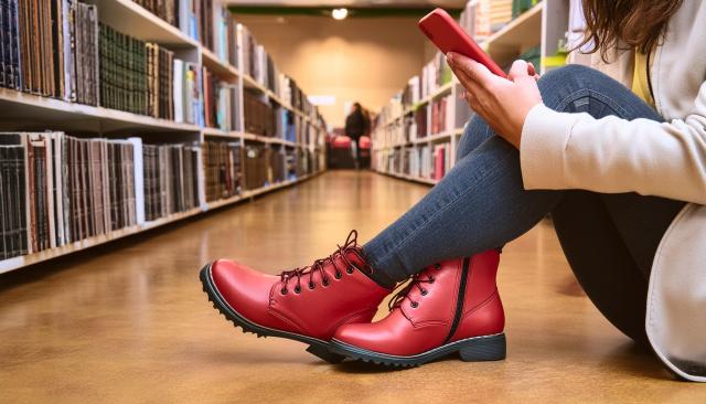 decorative image of student using a phone in the library