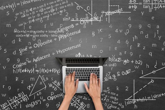 computer sitting on a chalkboard covered with equations
